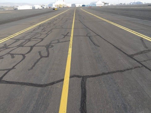 This picture shows an overview photo of an asphalt pavement with visible transverse and longitudinal cracking over a larger area of the pavement surface.  The PCI of the pavement in the image is 60.