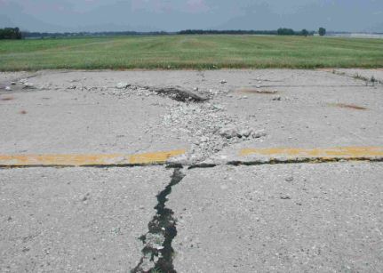 Overview photo of a transverse PCC joint with a high-severity blowup.  Both slabs have considerable spalling due to the blowup.