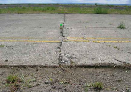 Overview photo of a transverse PCC joint with a low-severity blowup.  A slight difference in height is noticable between the two slabs.